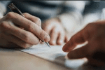 Mão segurando uma caneta pronto para assinar um papel e fechar um negócio
